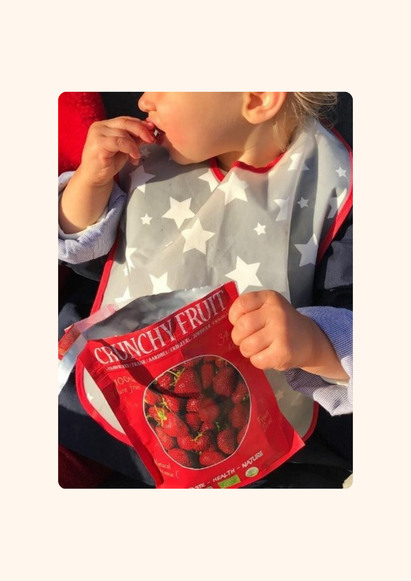 Un enfant souriant tient un paquet de CRUNCHY FRUIT Fraise biologiques et lyophilisées, en train de savourer un morceau de fraise croquante. Le paquet coloré est ouvert, révélant des fraises sans sucres ajoutés, parfaites pour une collation saine et gourmande. Ce moment montre le plaisir d'une pause snack nutritive, idéale pour les enfants.